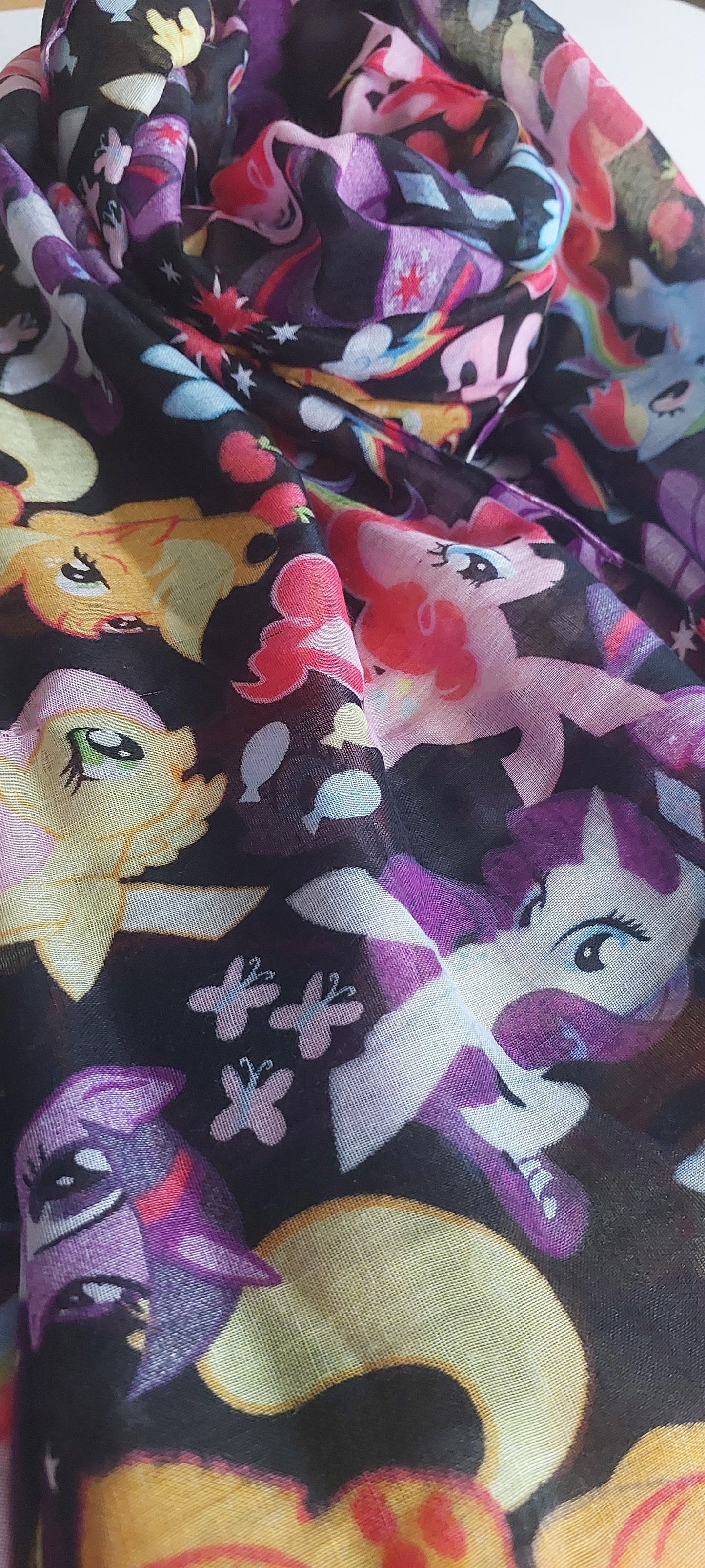Close-up of fabric with colourful cartoon pony characters on a black background