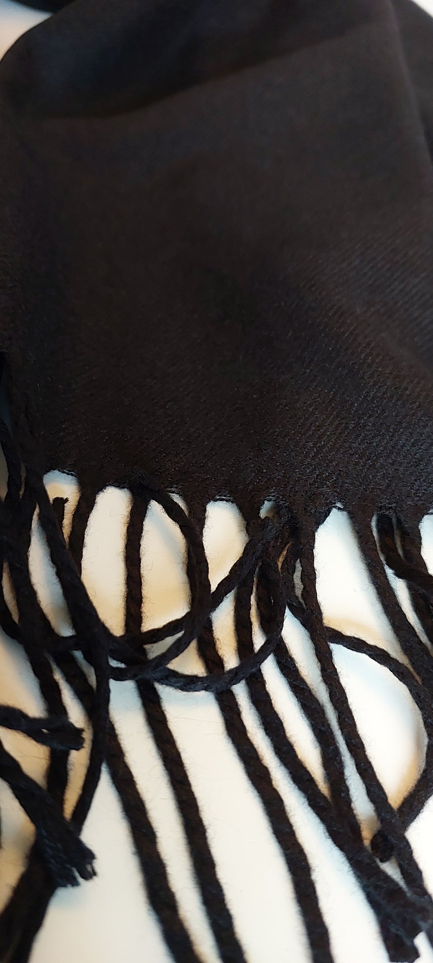 Close-up of a black pashmina with fringes on a white background