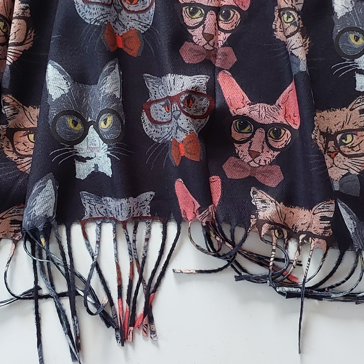 Close up of Scarf with cat pattern on a white background, highlighting the tassels