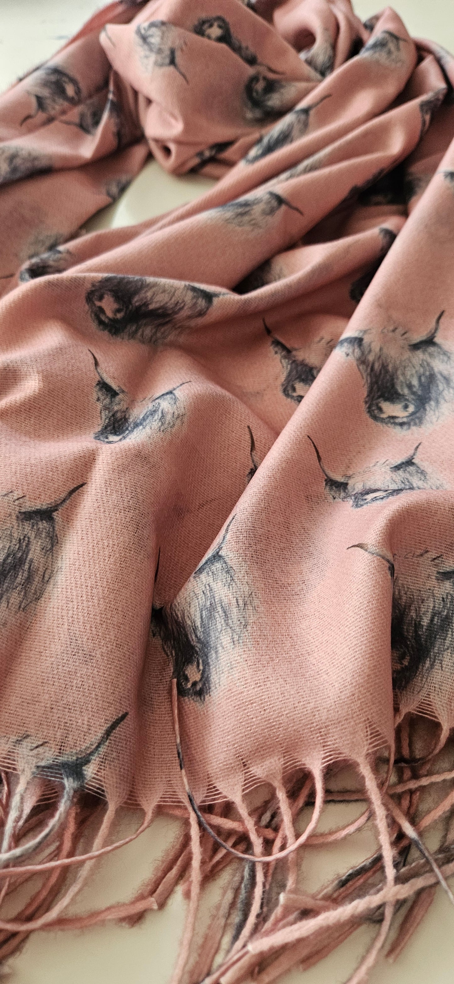 Pink scarf with black & White highland cows and tassels on a light background