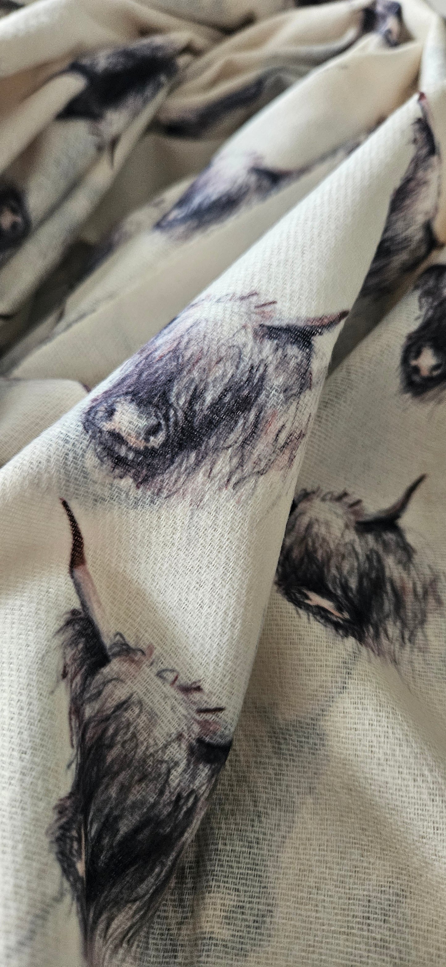 Close-up of cream scarf with black and white highland cow print on