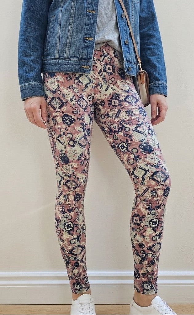 Person wearing a denim jacket, floral leggings, and white trainers against a plain background
