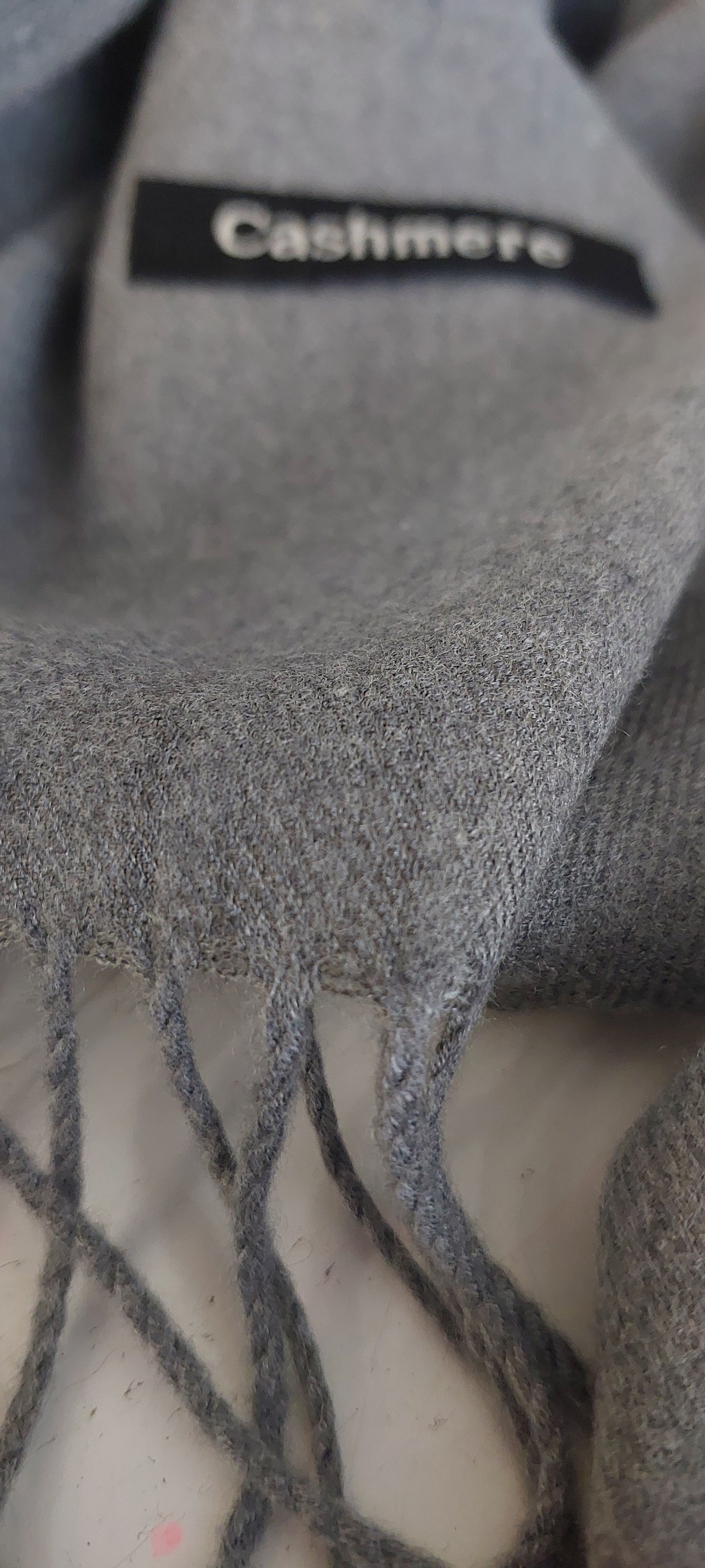 Gray cashmere scarf with visible Cashmere logo on a white surface