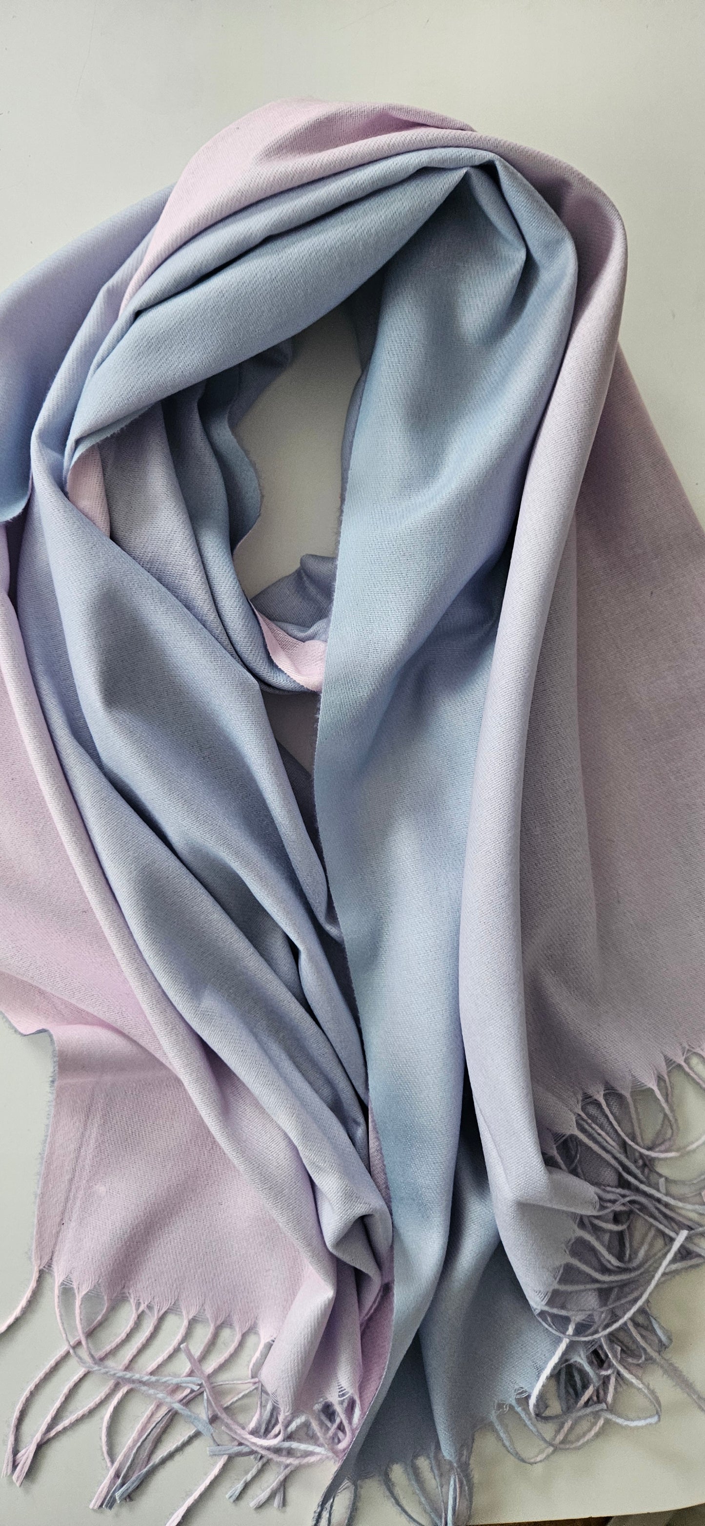 Light Blue and pink folded scarf with tassels on a light background