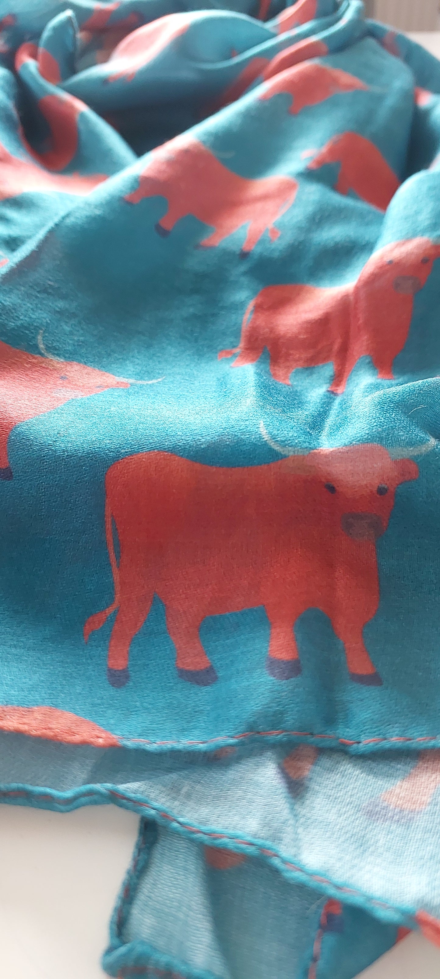 Close-up of scarf with ginger Highland cow pattern on white background