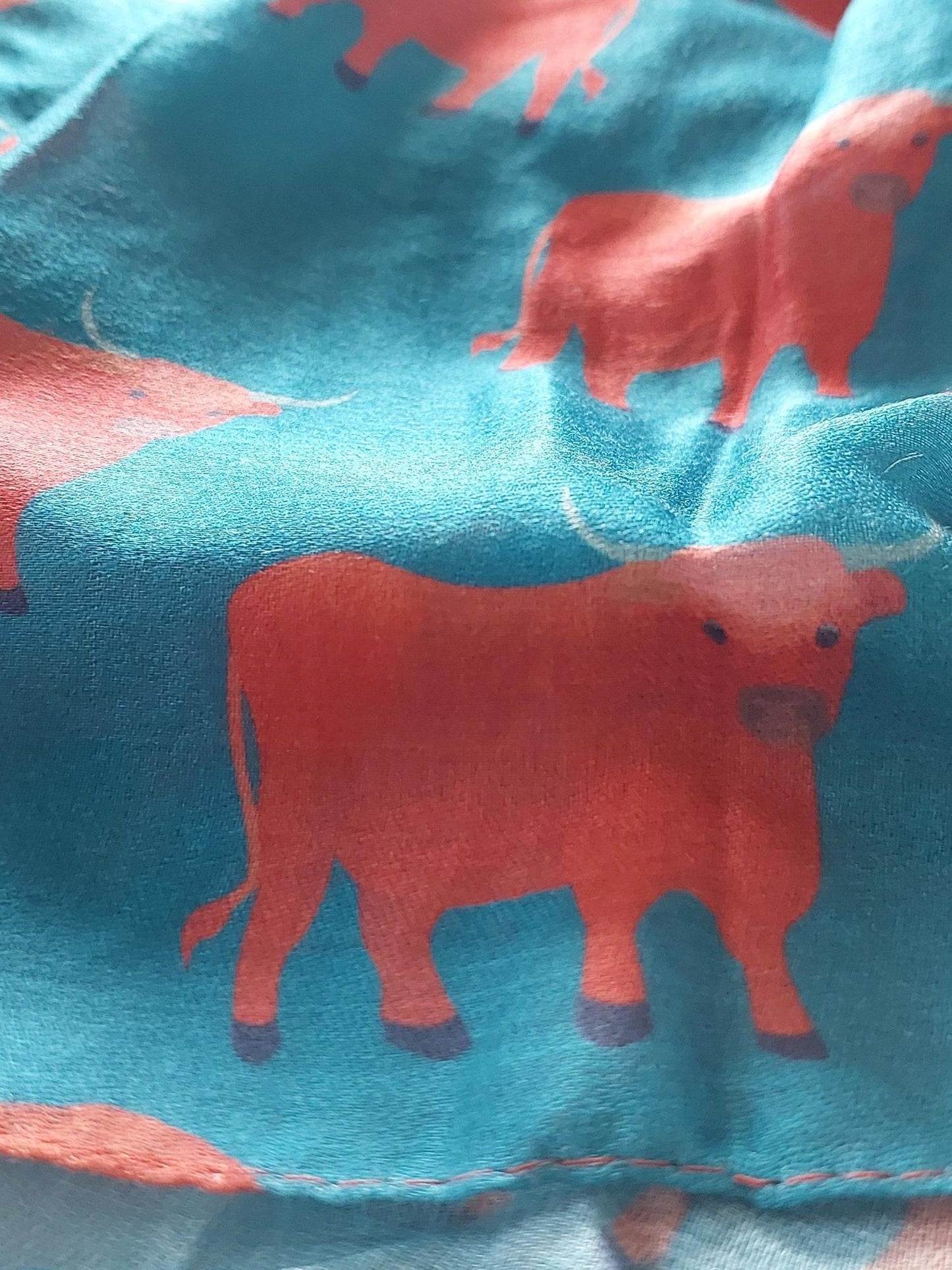 Close-up of scarf with ginger Highland cow pattern on white background