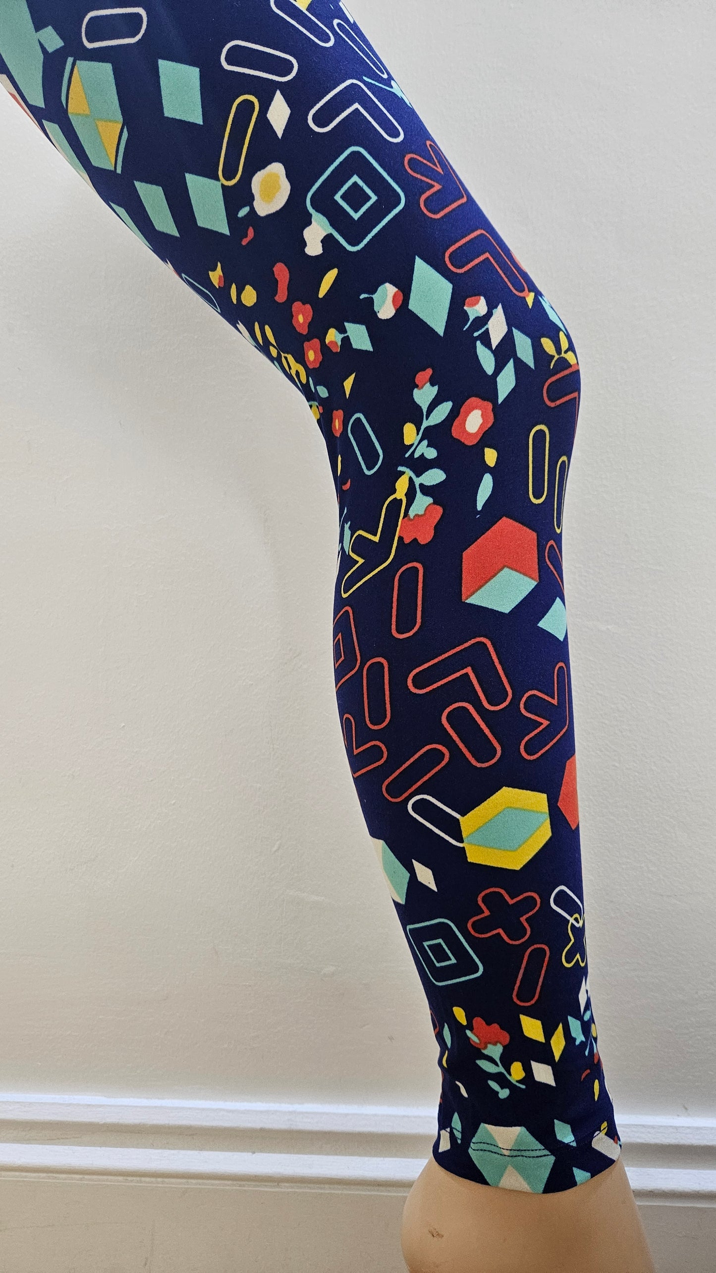 Colourful geometric patterned leggings on a mannequin leg against a white background