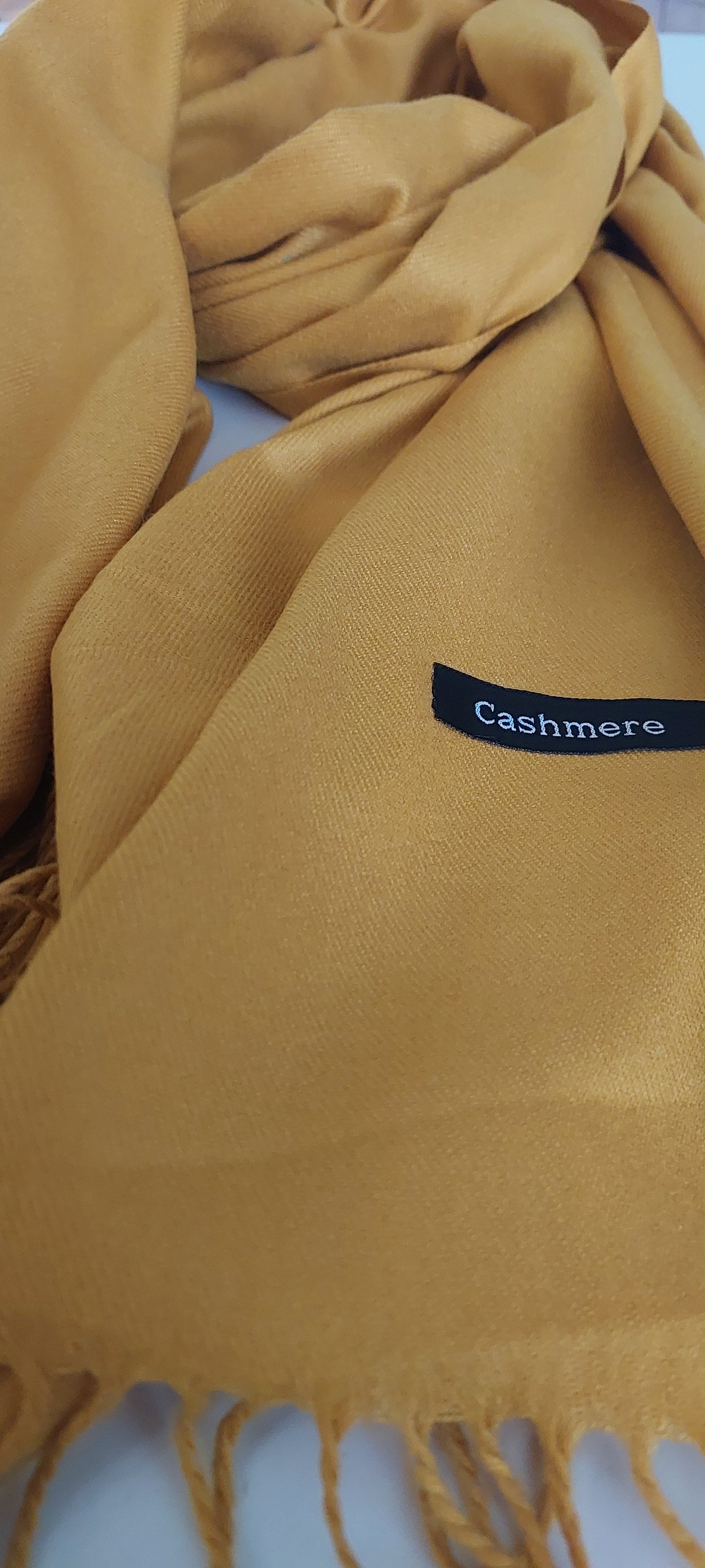 Close-up of a mustard yellow fabric with a 'Cashmere' label.