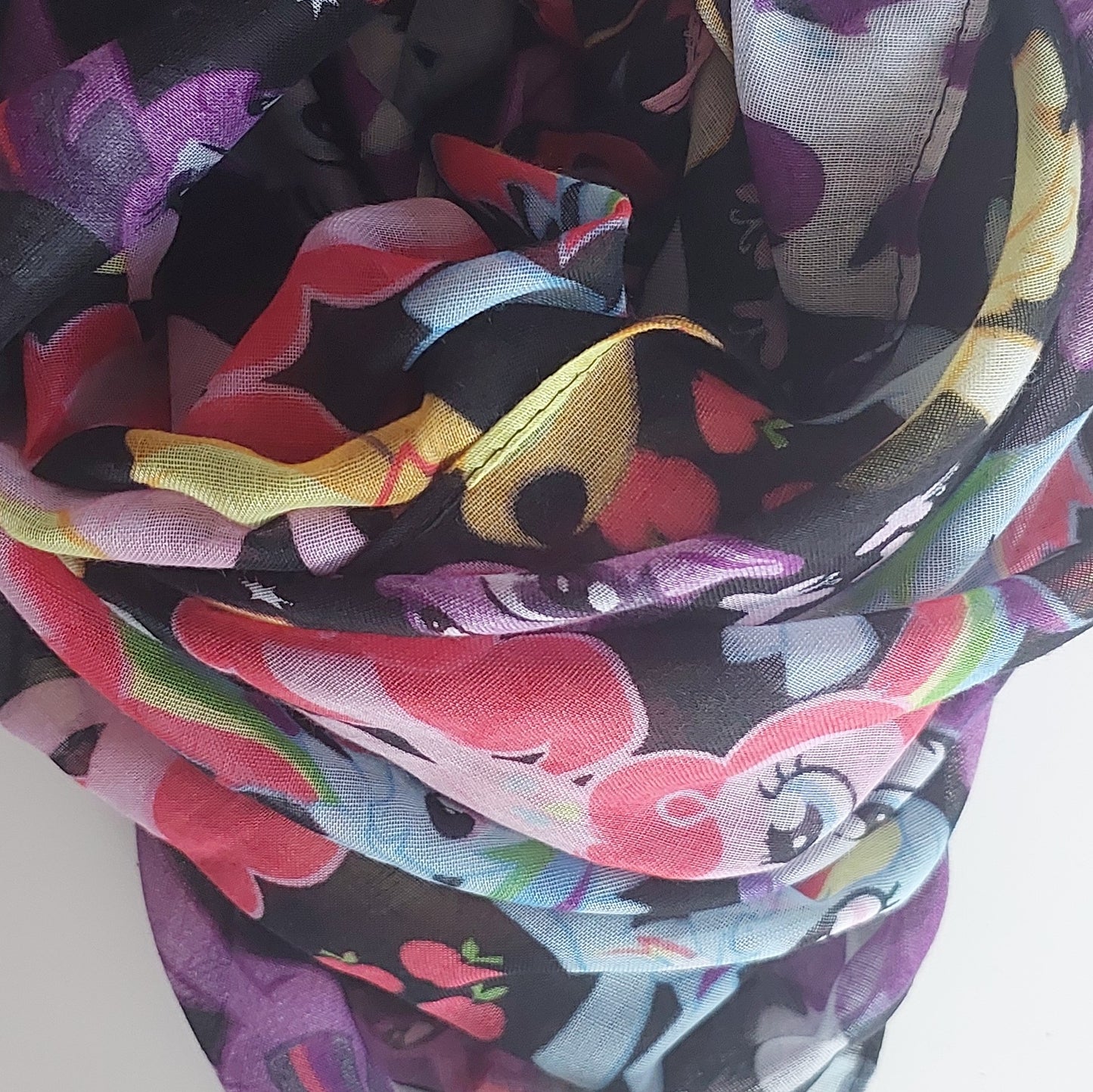 Colourful scarf with cartoon pony designs on a white background