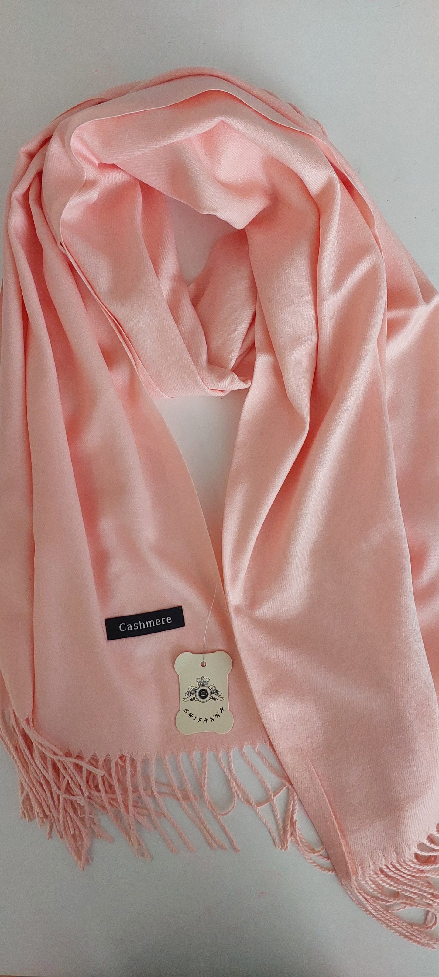 Pink scarf with a cashmere tag on a white background