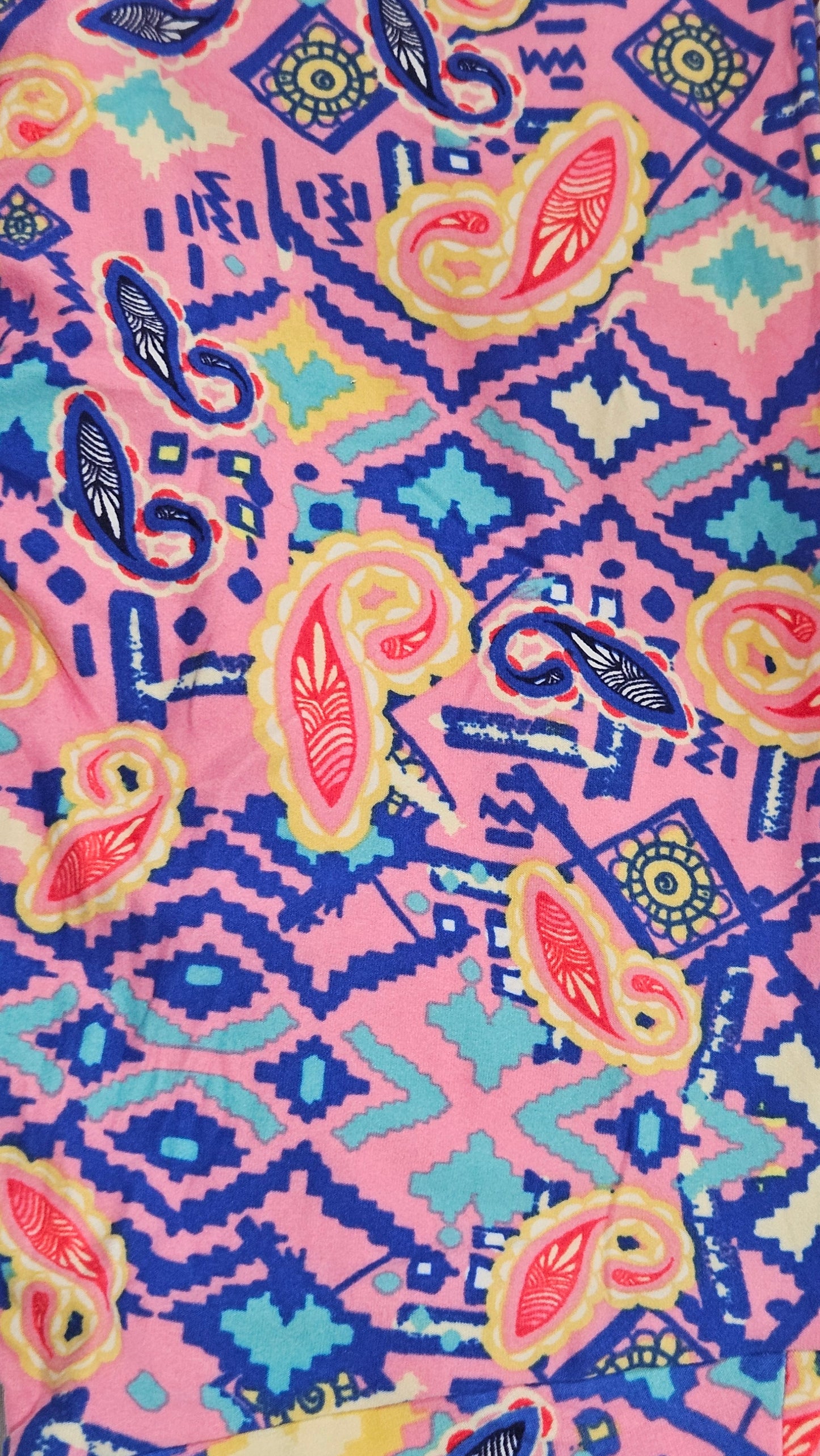 Colorful fabric with a paisley pattern and geometric shapes on a pink background