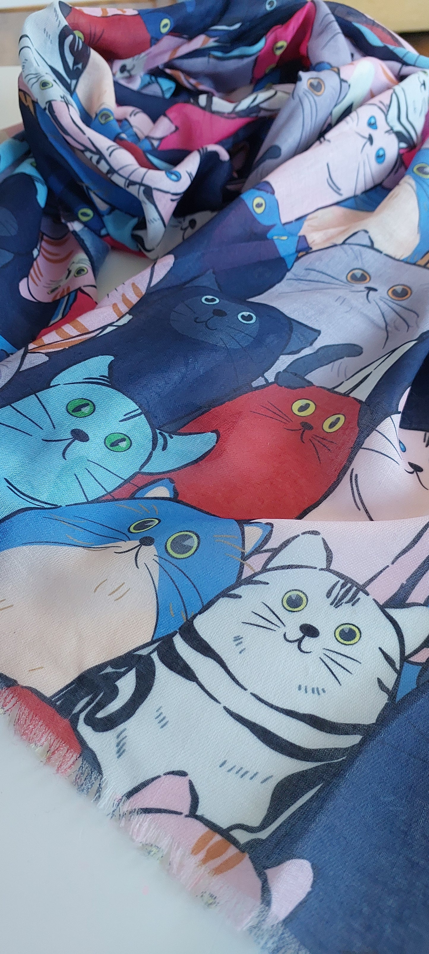 Scarf with colourful cat pattern on a blue background and fringing