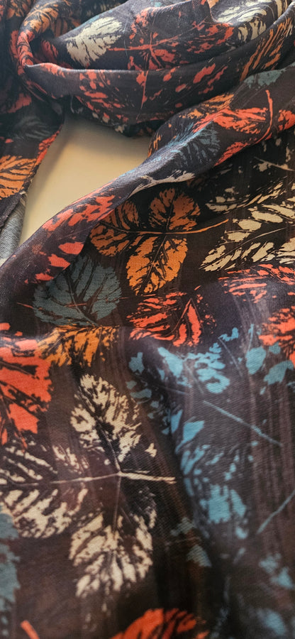 Close up image of black scarf with autumnal coloured leaves on