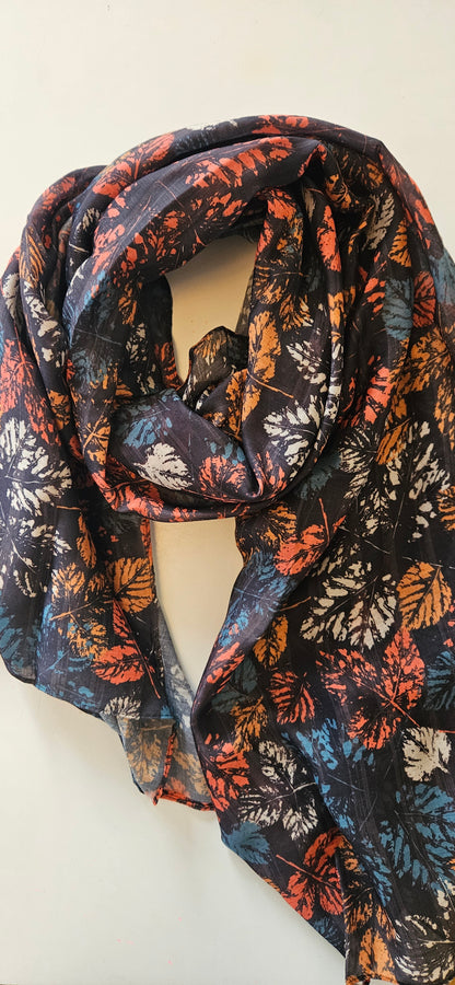 Black scarf with autumnal coloured leaves on, in red, orange and teal