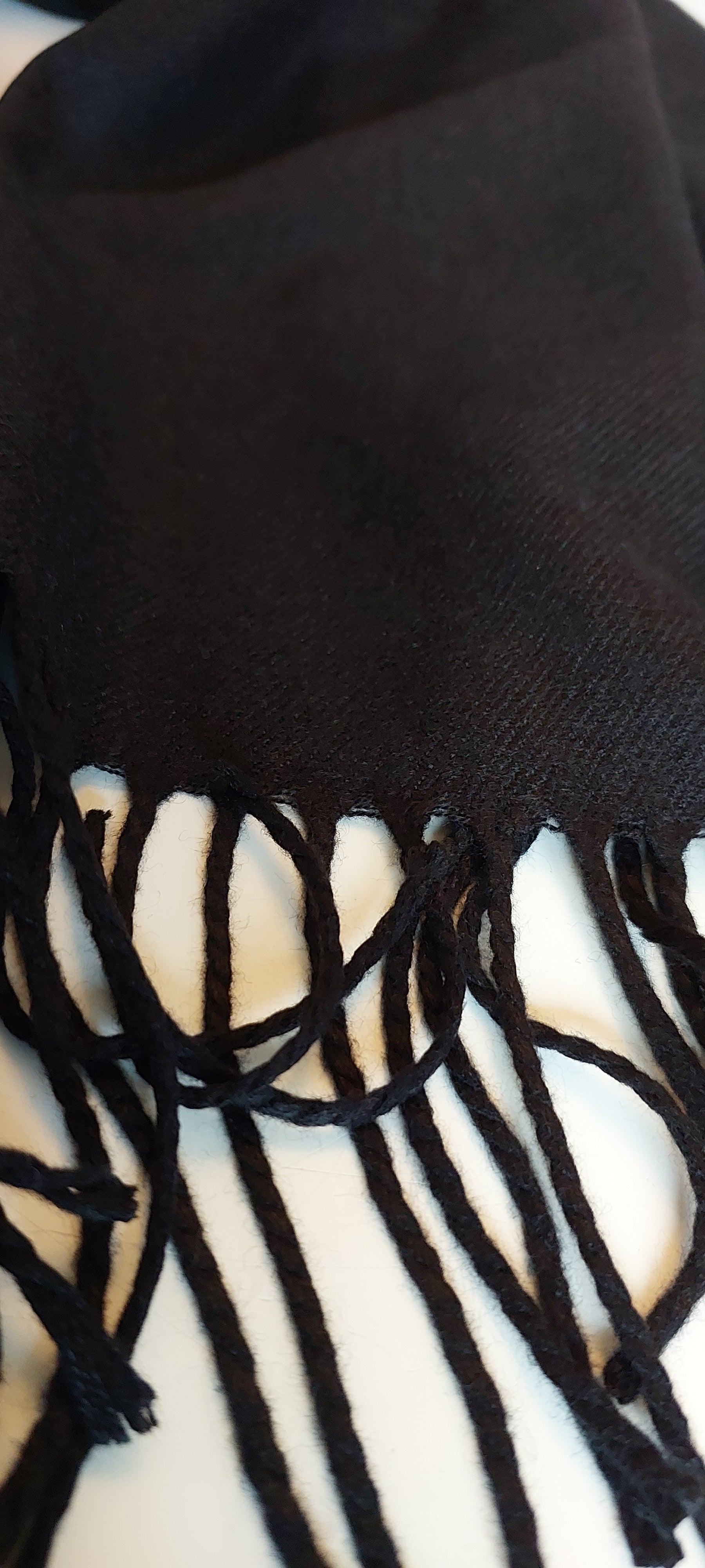 Close-up of a black pashmina with fringes on a white background
