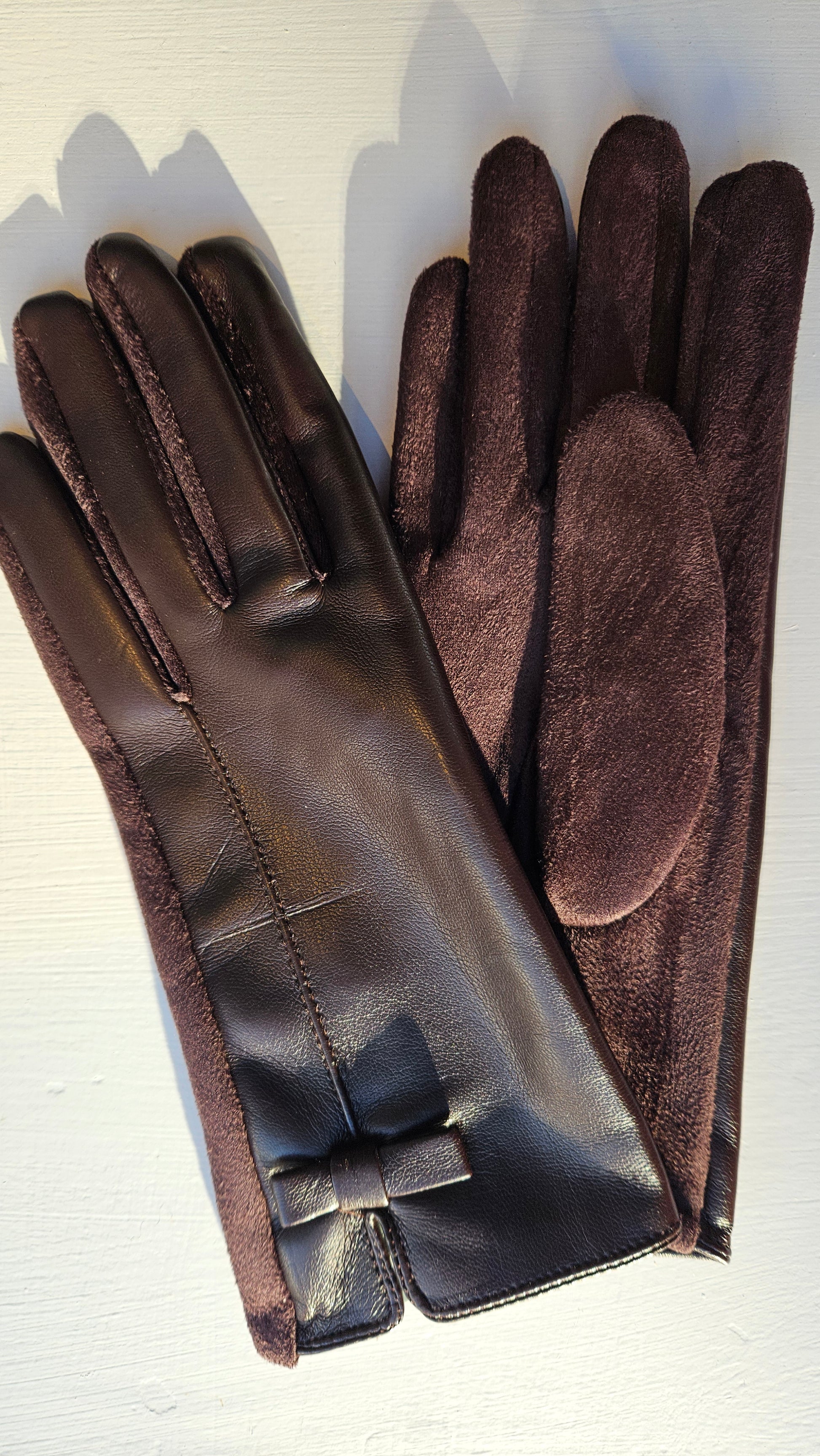 One brown leatherette glove facing up and one glove facing down on a white background