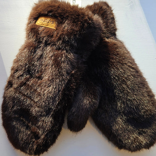 Pair of brown fur mittens on a white surface with a visible brand tag.
