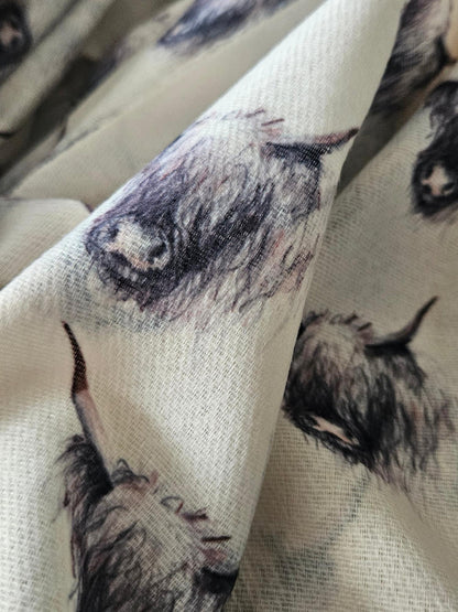 Close-up of cream scarf with black and white highland cow print on 