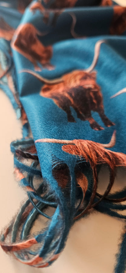 Close-up of a blue scarf with brown Highland Cows on a white background
