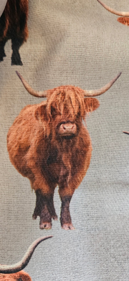 Close-up of a scarf with printed longhorn cattle design on a grey background