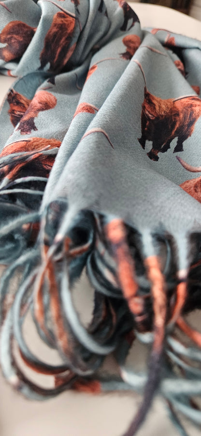 Close-up of a Mint-green scarf with highland cow pattern on a white background