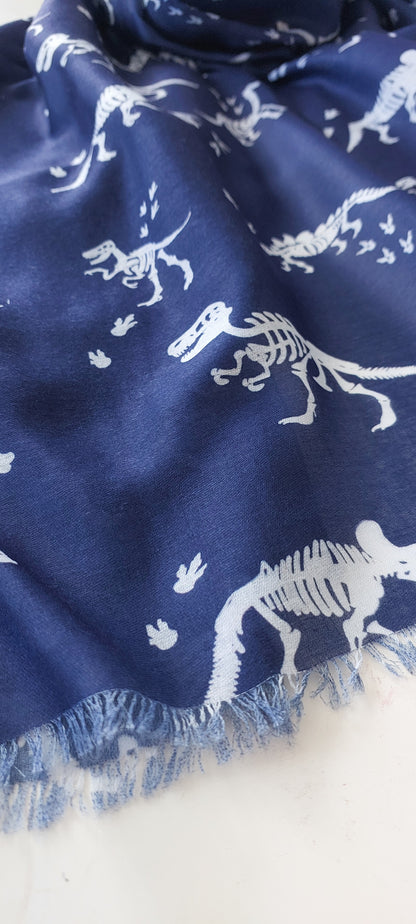 Navy blue scarf with white dinosaur skeleton patterns and fringing on a white background