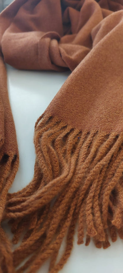 Close up image of tassels on rusty brown winter Shimena Scarf on a white background