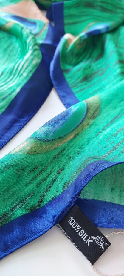 Green and blue silk fabric with a tag indicating '100% silk' on a white background