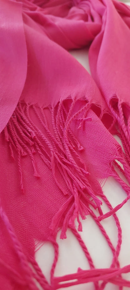 Close-up of a bright pink scarf with fringes on a white background