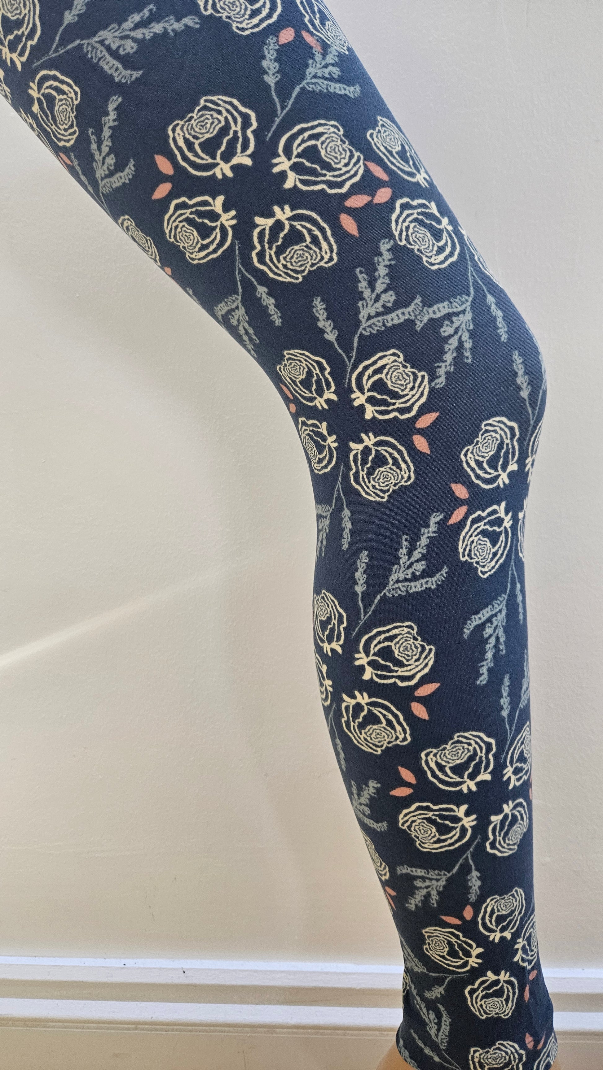 Navy blue leggings with cream floral patterns on a white background