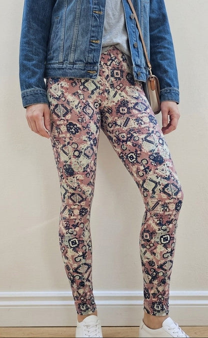 Person wearing a denim jacket, floral leggings, and white trainers against a plain background