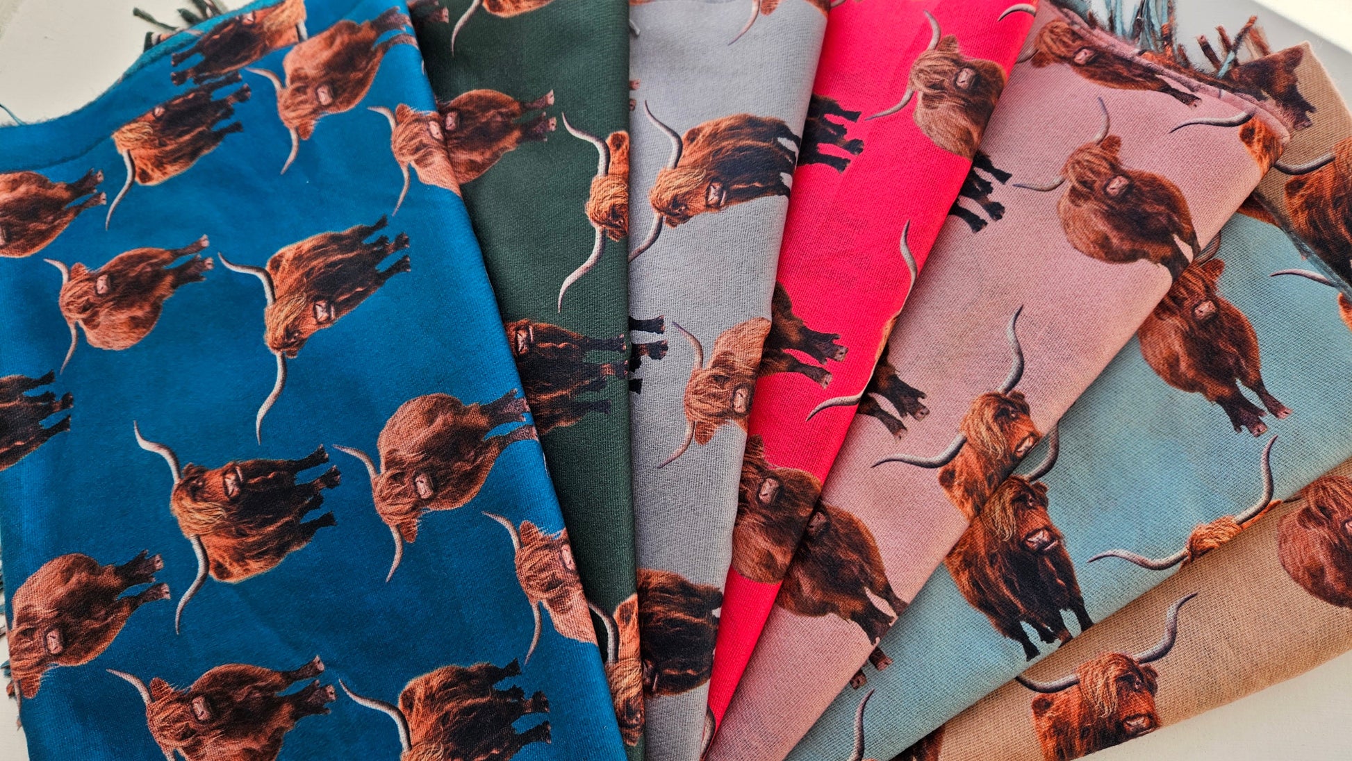 Collection of pashminas with Highland Cow pattern on various colors