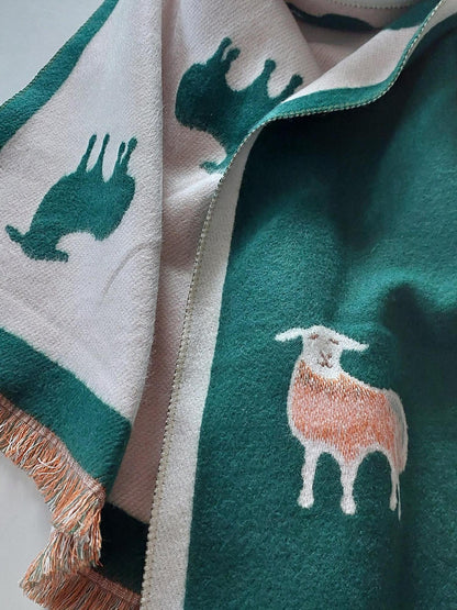 Green scarf with sheep patterns and fringe on a white background