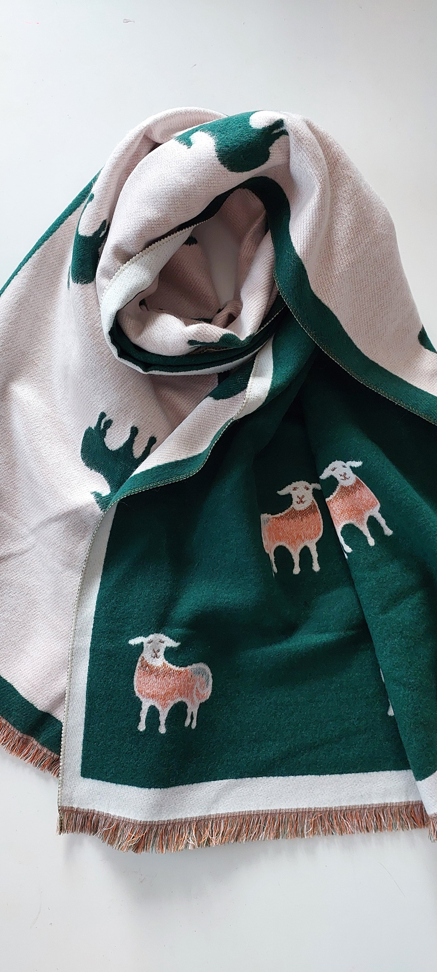 Green and white scarf with sheep designs on a white background