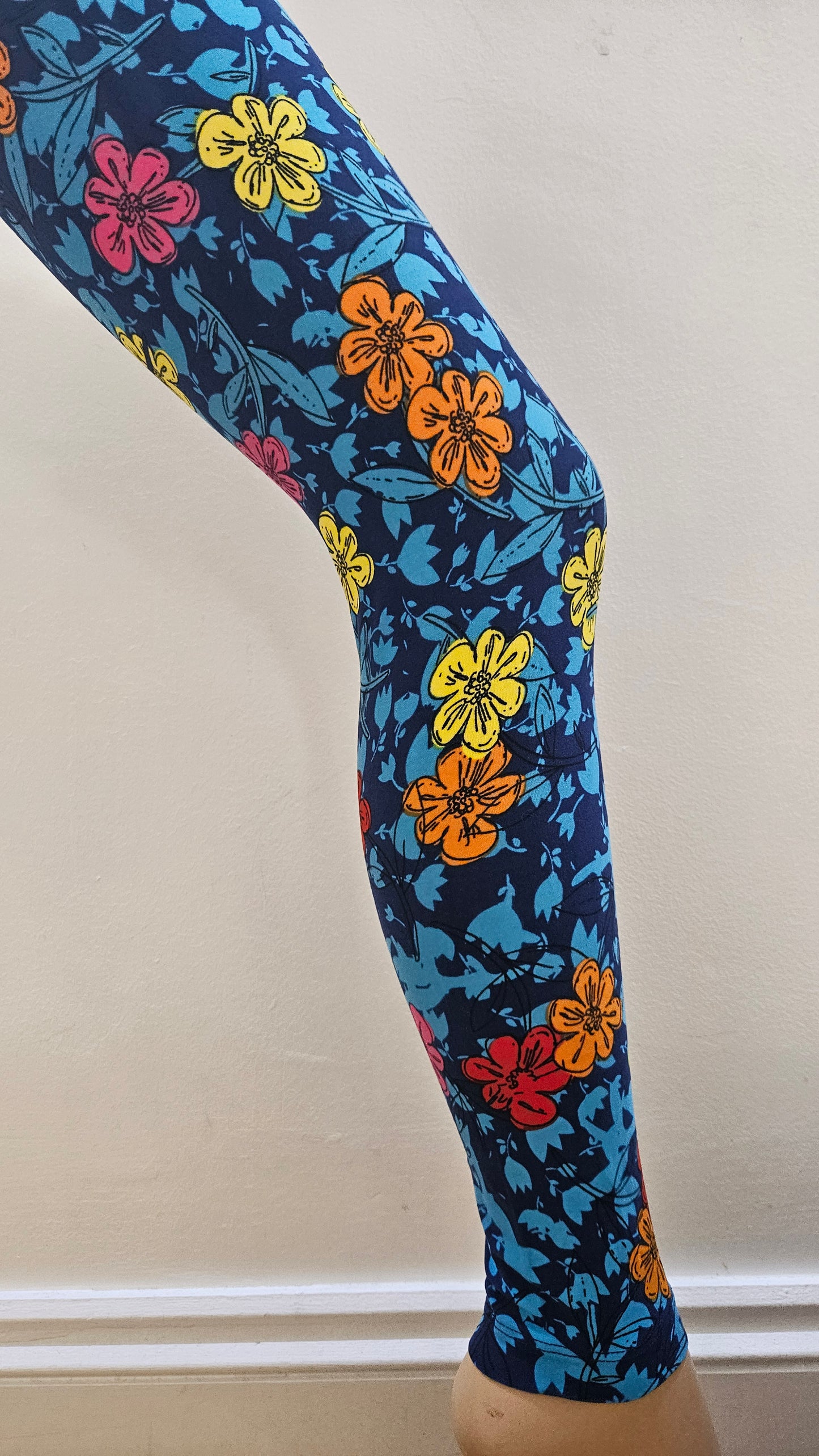 Colourful floral-patterned leggings on a mannequin leg against a neutral background