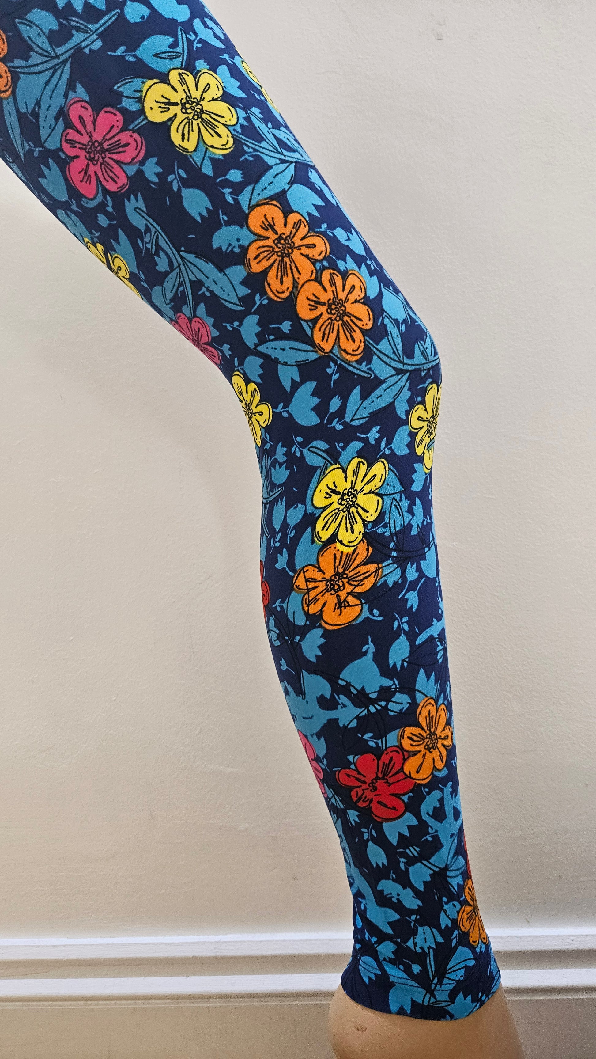Colourful floral-patterned leggings on a mannequin leg against a neutral background