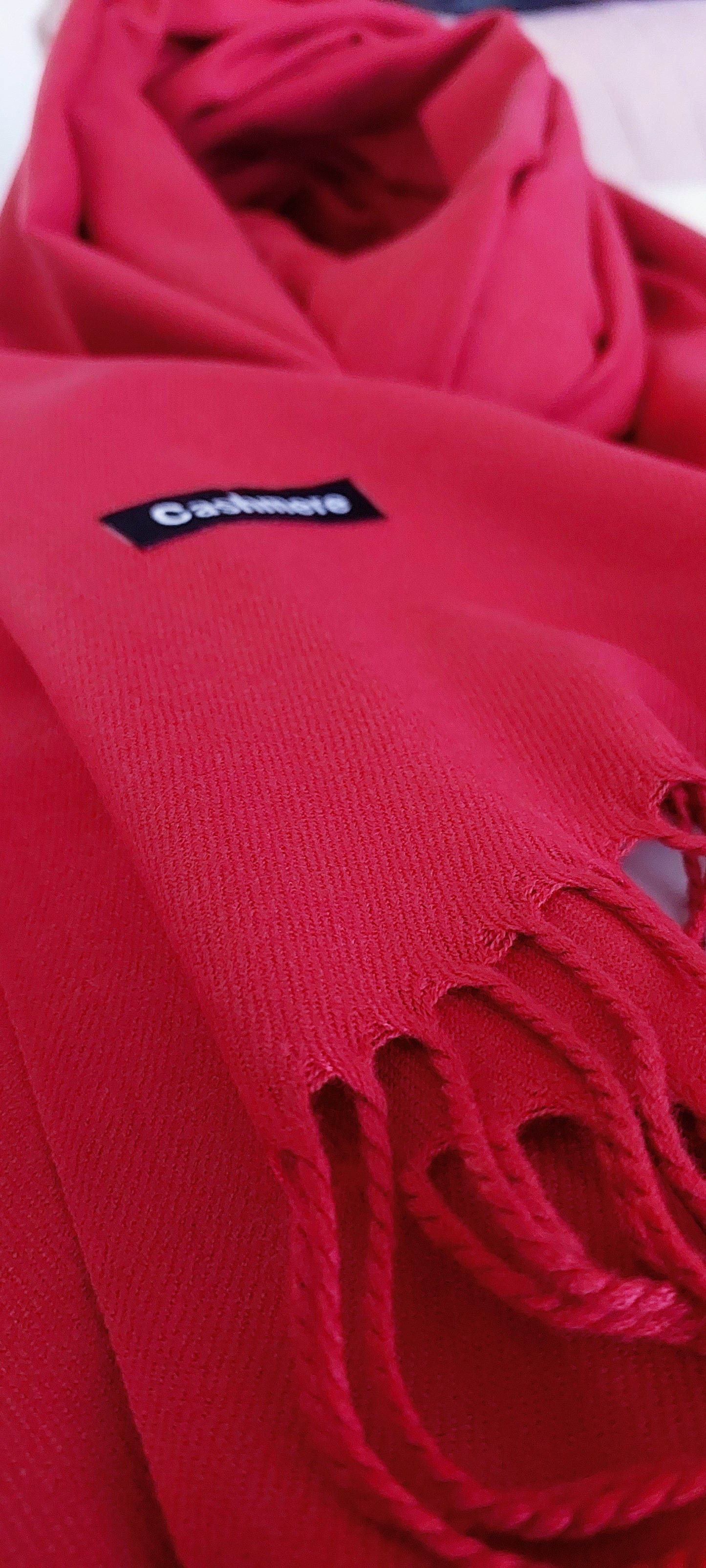 Red pashmina with a visible Cashmere logo on a blurred background