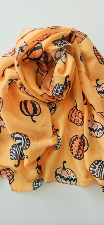 Orange scarf fabric with White Black and Orange patterned pumpkins on it, laid flat on a white background