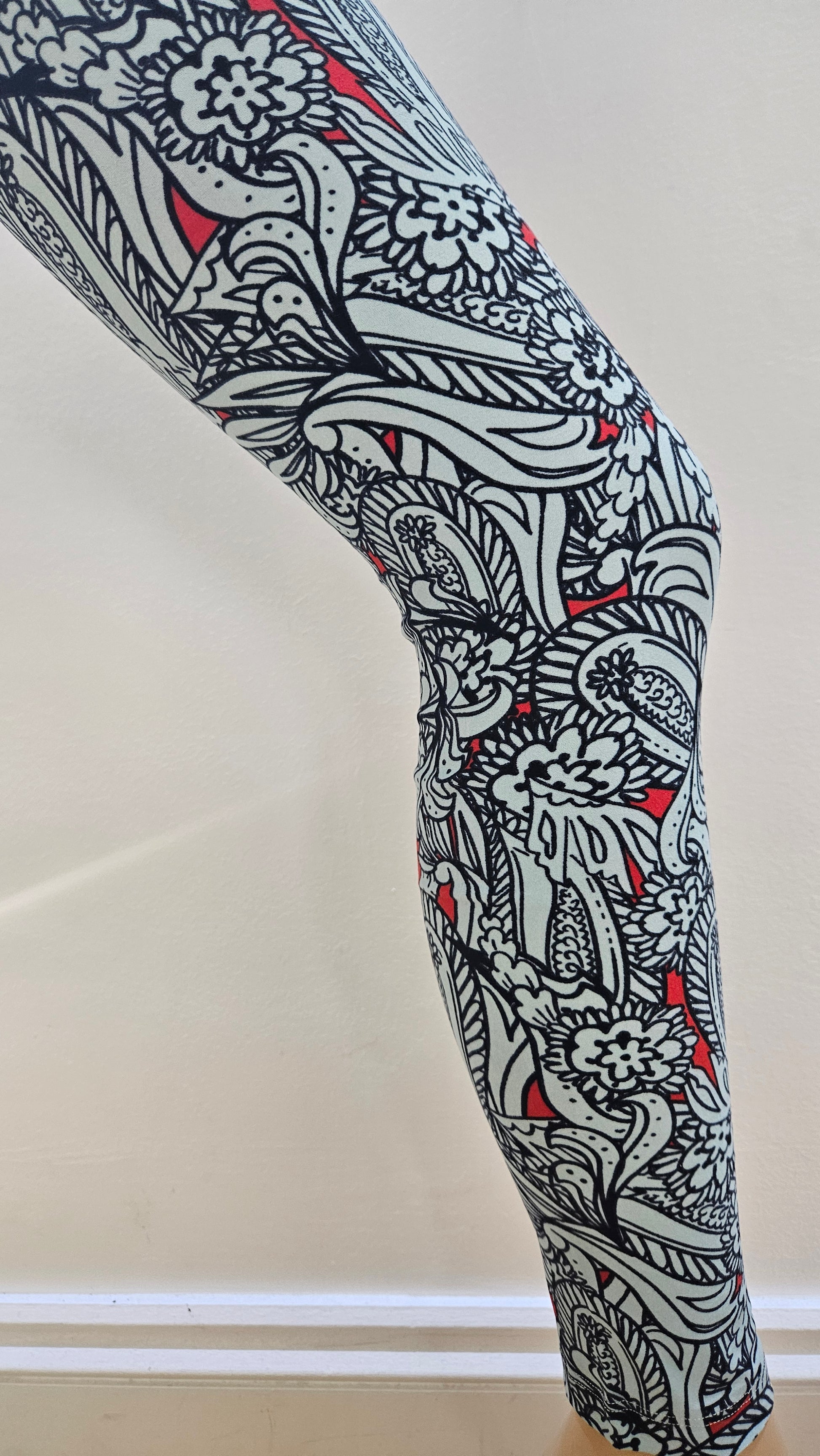 Decorative leggings with black, pale blue, and red pattern on a plain background
