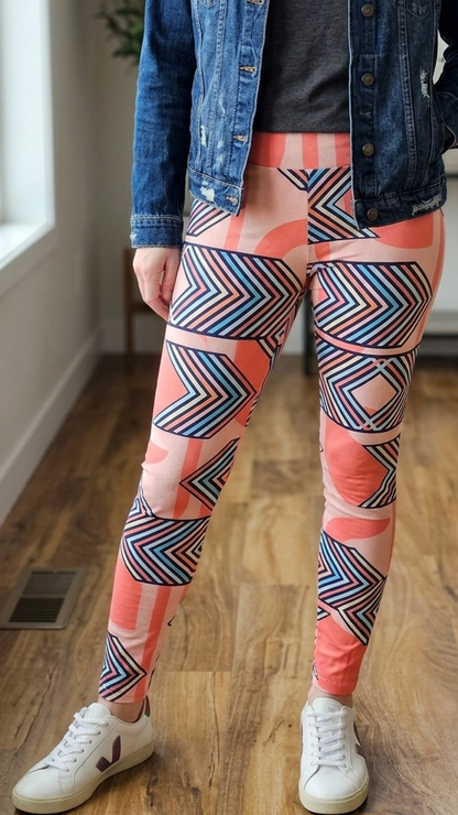 Person wearing a denim jacket, gray shirt, and colorful geometric-patterned leggings indoors.