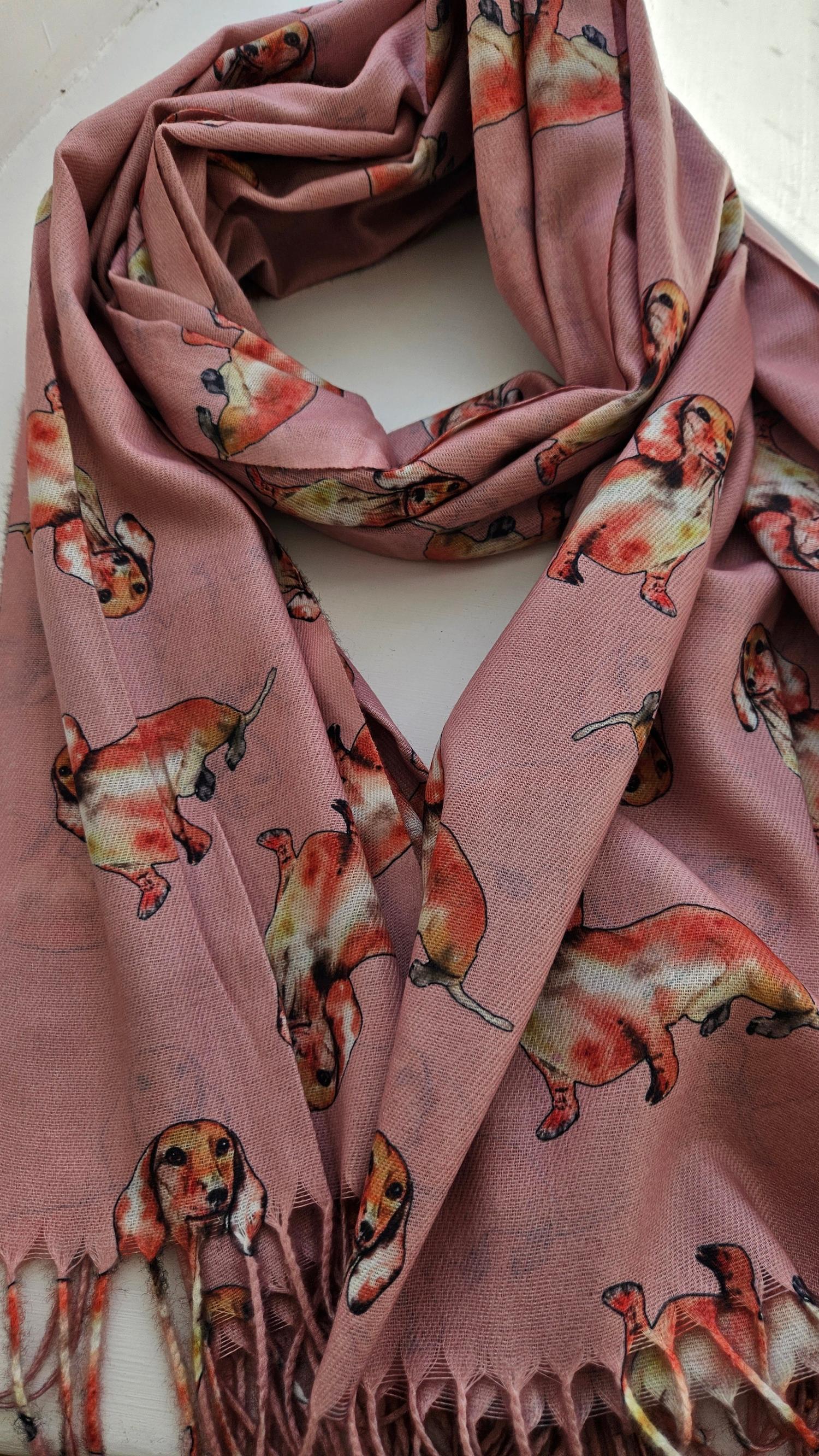 Pink pashmina with tan coloured sausage dogs pattern on a white background