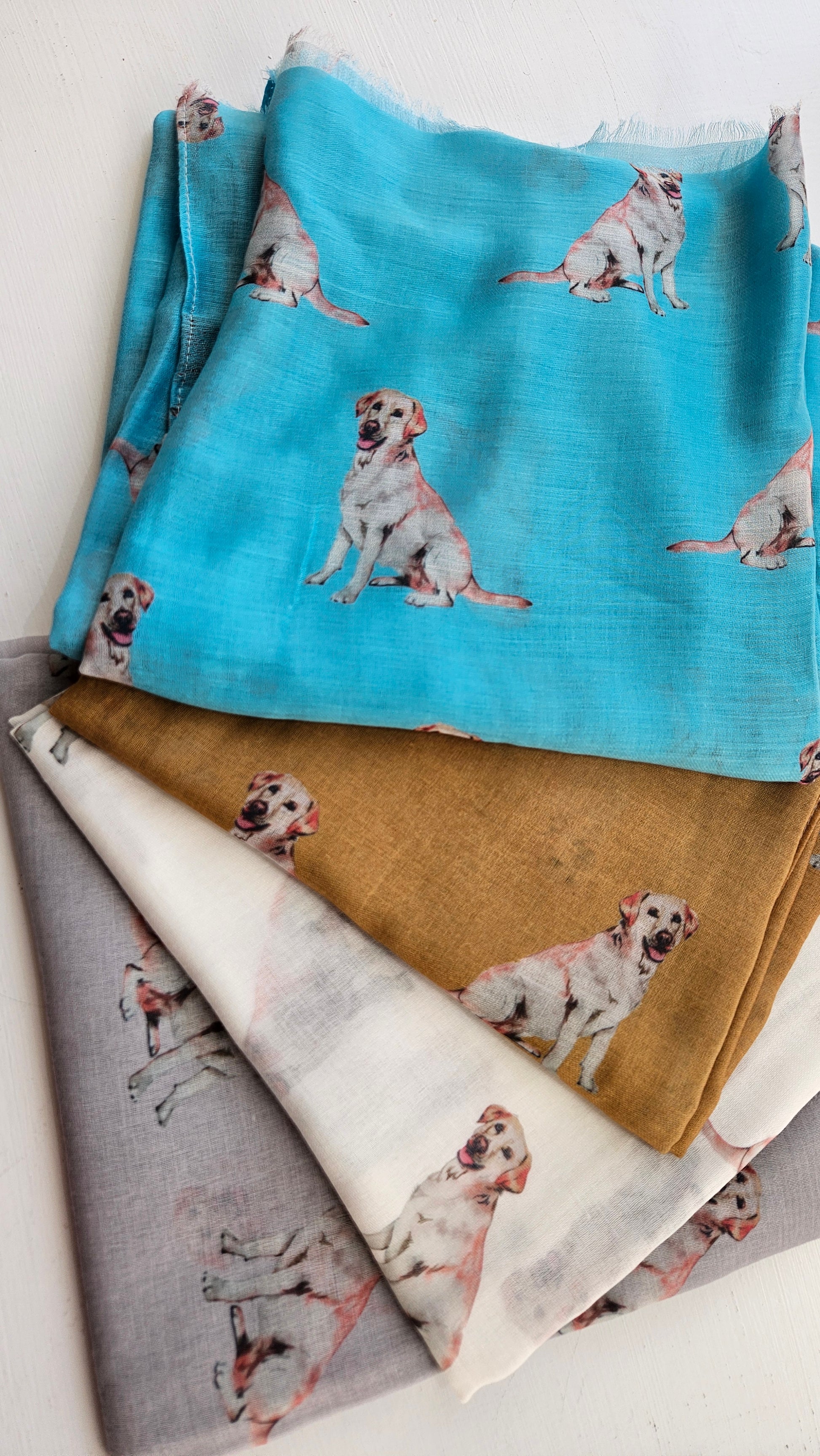 Four colourful folded scarves with Labrador dog pattern on a white background