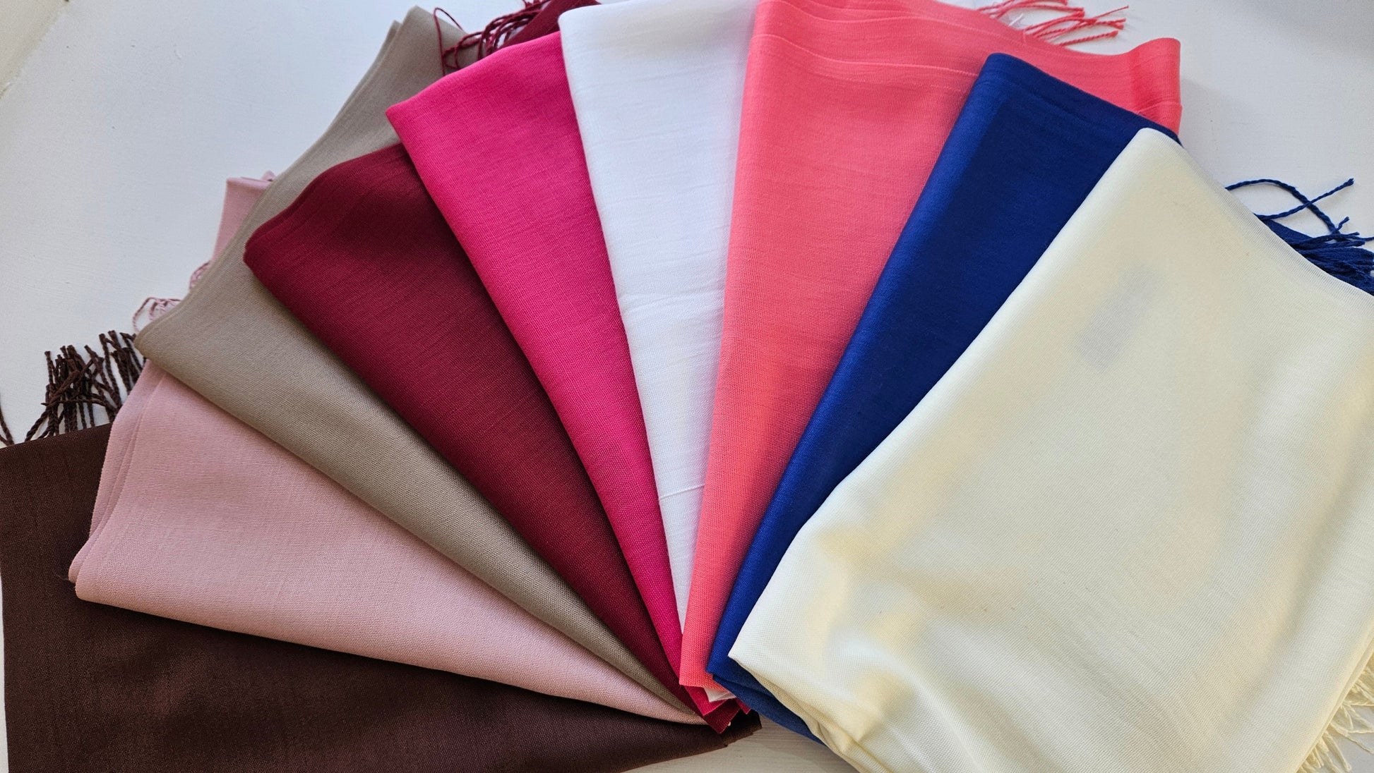 Set of folded fabric scarves in various colors on a white background