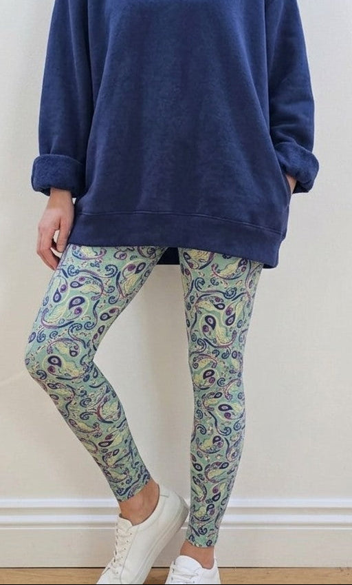 Woman wearing a navy hoodie and patterned leggings against a white wall.