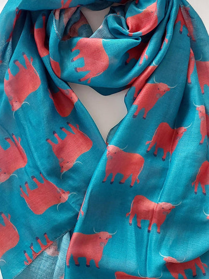 Teal scarf with red Highsland cow patterns on a white background