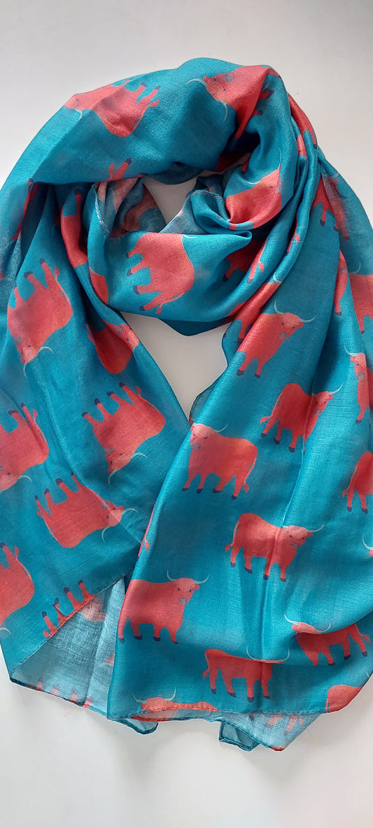 Teal scarf with red Highsland cow patterns on a white background