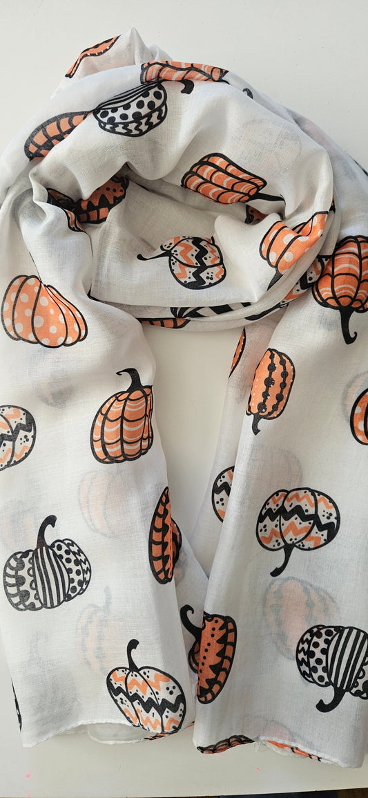 White Scarf with Black, white and orange patterned pumpkins on it, laid flat on a white background,